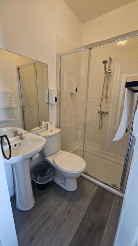 a bathroom with a toilet and a sink and a shower at The Strand Hotel in Eastbourne