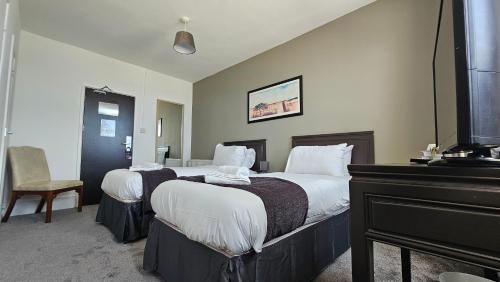 a hotel room with two beds and a piano at The Strand Hotel in Eastbourne