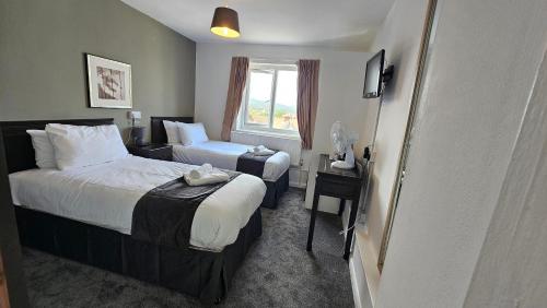 a hotel room with two beds and a window at The Strand Hotel in Eastbourne