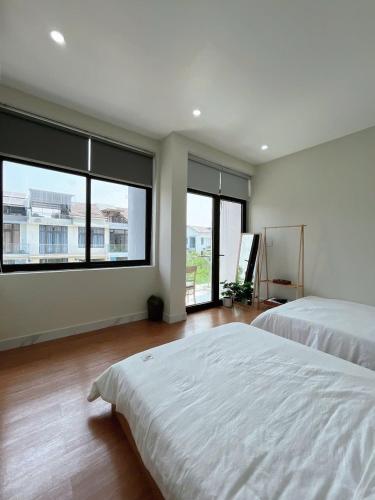 a large bedroom with two beds and large windows at Minh Anh Villa & Apartment in Thôn Trường Giang