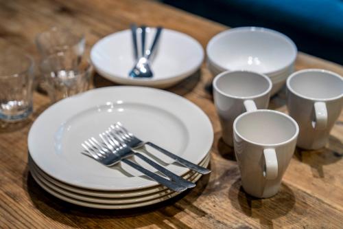a wooden table with white plates and forks and cups at Taketo Stay Kotoni 101 in Sapporo