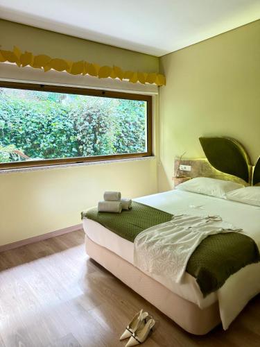 a bedroom with a bed and a large window at Beleza Serra Guide Hotel in Geres