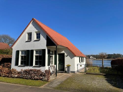 een wit huis met een oranje dak bij Luxe villa aan het meer in Heel