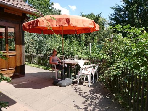 a woman sitting at a table under an umbrella at Ferien-und Bauernhof Gauster in Trebel