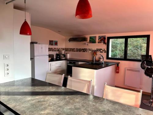 Il comprend une cuisine équipée d'appareils électroménagers blancs et de lampes suspendues rouges. dans l'établissement DOELAN superb apartment with sea views on all sides, à Clohars-Carnoët