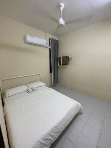 een slaapkamer met een wit bed in een kamer bij Qisa Guesthouse 03 in Arau