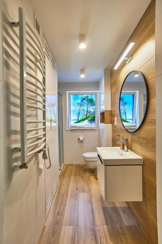 a bathroom with a toilet and a sink and a mirror at Forest Apartment in Pobierowo