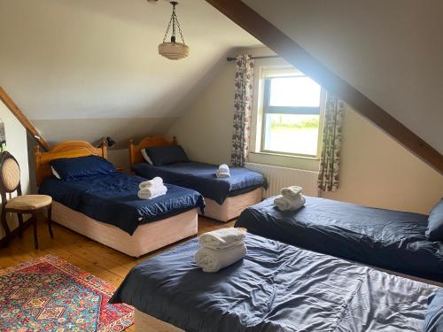 a attic room with three beds and a window at Heathervillefarm Blennerville rooms in a house in Blennerville
