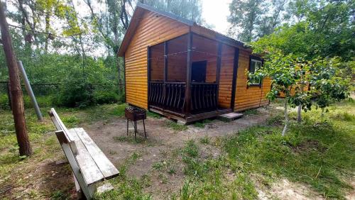 a small wooden cabin in a field with a bench at Сімейна Садиба Пірнове in Pirnove