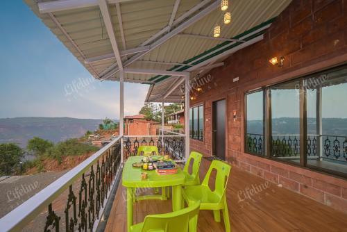 a green table and chairs on a balcony at Lifeline Villas - Wonderment Luxurious Valley View 5Bhk Villa in Mahabaleshwar