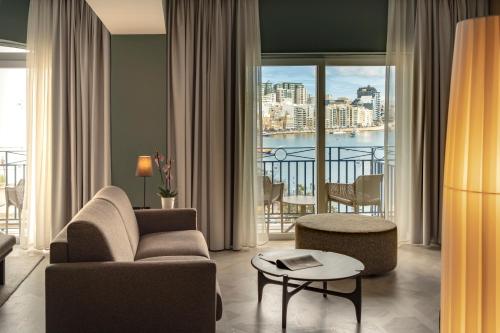 a living room with a couch and a chair and a balcony at Waterfront in Sliema
