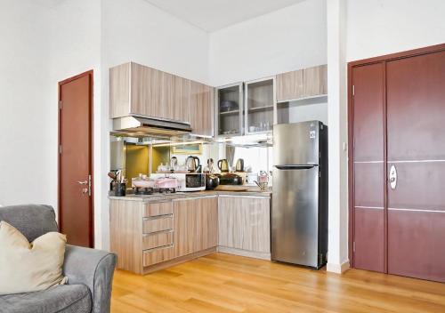 a kitchen with a stainless steel refrigerator and wooden cabinets at 2BR Lucky Tower Residence Jakarta Old Town Top Floor Condo in Jakarta