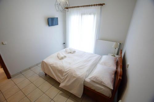 a bedroom with a bed with white sheets and a window at Perasma2 in Perama