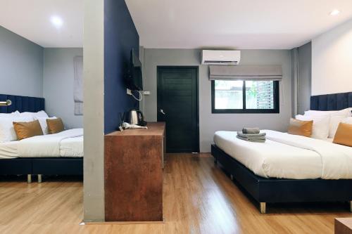 a hotel room with two beds and a window at Castle Black Bangkok in Bangkok