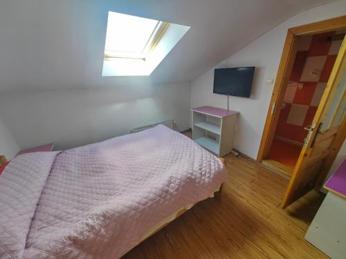 a bedroom with a bed and a window and a television at Casa bunicilor dor de Bucovina in Câmpulung Moldovenesc