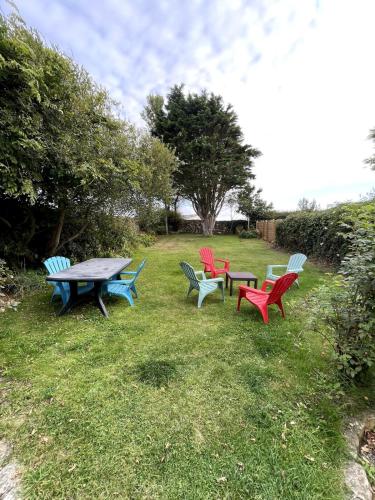 a group of picnic tables sitting in the grass at Maison à quelques mètres de la mer in Saint-Jean-du-Doigt