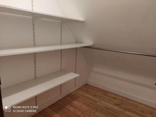 an empty closet with white shelves and a wooden floor at Maison à quelques mètres de la mer in Saint-Jean-du-Doigt