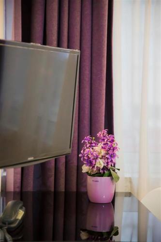 a vase of flowers on a table in front of a curtain at Cyprus Apart Hotel in Mağusa