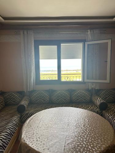 a bed in a bedroom with two windows at Appartement Sidi Bouzid in El Jadida