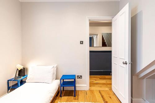 a small bedroom with a bed and a blue stool at Stylish Kings Cross Apartment with Garden in London