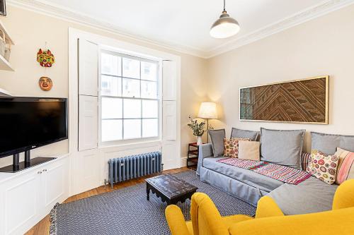 a living room with a couch and a tv at Stylish Kings Cross Apartment with Garden in London