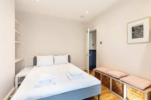 a small bedroom with a bed and two benches at Stylish Kings Cross Apartment with Garden in London