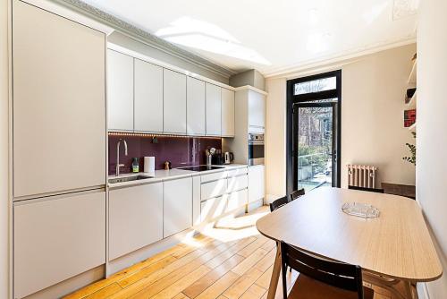a kitchen with white cabinets and a wooden table at Stylish Kings Cross Apartment with Garden in London