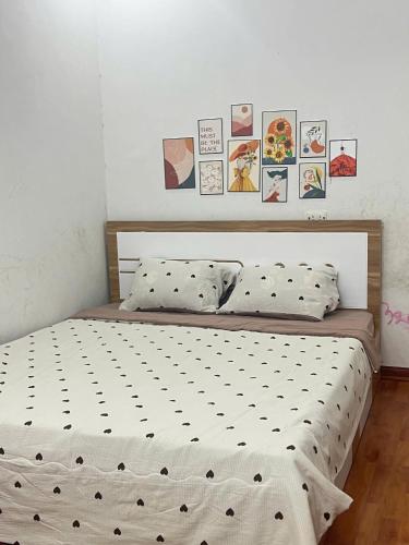 a bed in a bedroom with pictures on the wall at Ting Ting Homestay in Hai Phong