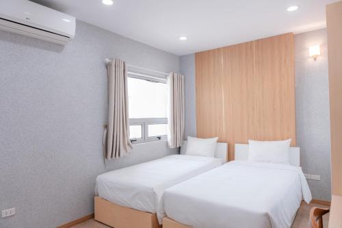 two beds in a small room with a window at Juna hotel in Thanh Hóa