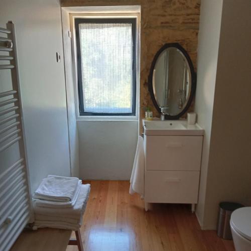 a bathroom with a mirror and a sink and a window at Casa do Faval in Senande