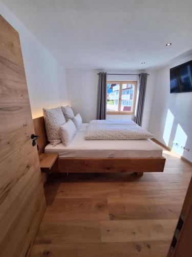 a large bed in a room with a window at Beim Hofar - die neuen Ferienwohnungen in Obermaiselstein in Obermaiselstein
