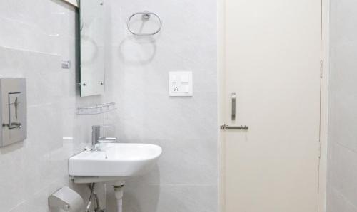a white bathroom with a sink and a mirror at Hotel Kamron Near Airport Road Sector 78 Mohali Chandigarh in Mohali