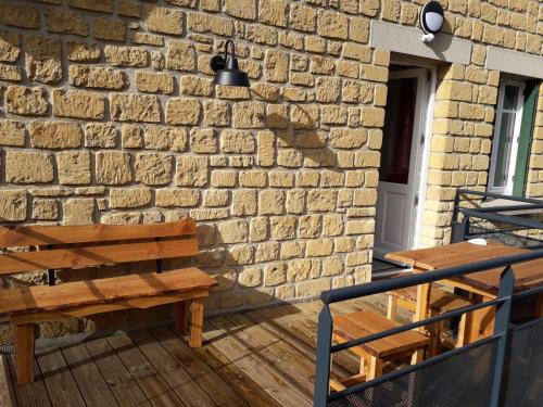 a brick wall with a wooden bench on a deck at Gîte Tante Aurore et chambres d'Hôtes in Chémery