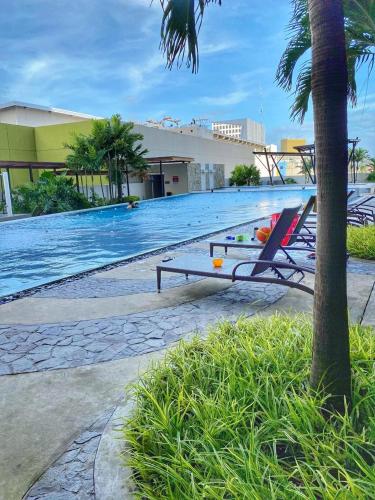 a pool with chairs and a table next to a building at Centrio Tower Cozy 1 Bedroom with City View in Cagayan de Oro