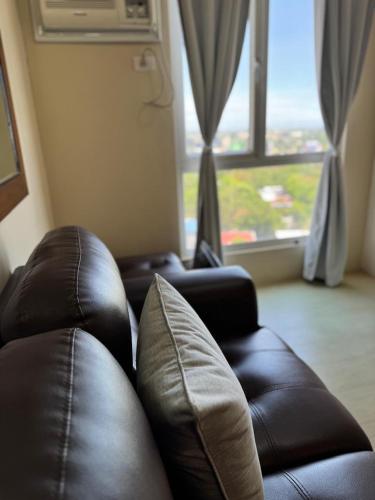 a living room with two leather couches and a large window at Centrio Tower Cozy 1 Bedroom with City View in Cagayan de Oro