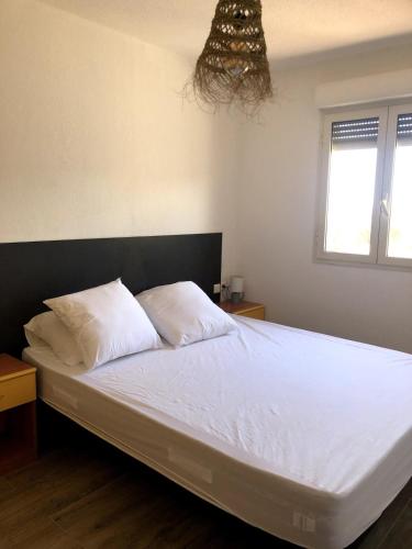 un lit avec des draps blancs et des oreillers dans une chambre dans l'établissement Villa climatisée vue mer Porto-Vecchio, à Sainte-Lucie de Porto-Vecchio