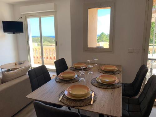 une salle à manger avec une table et des chaises en bois dans l'établissement Villa climatisée vue mer Porto-Vecchio, à Sainte-Lucie de Porto-Vecchio