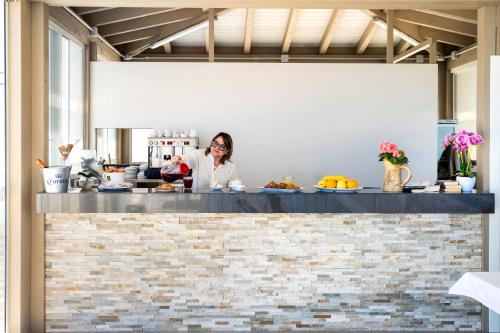 a woman standing behind a counter in a kitchen at Hotel Antica Cascina Del Golfo in Scopello