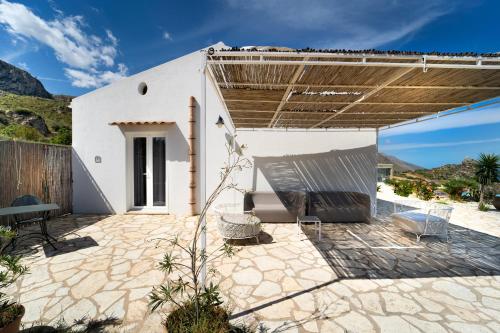 a patio with a white building with a roof at Hotel Antica Cascina Del Golfo in Scopello
