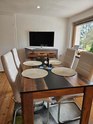 a dining room with a table with chairs and a television at Ferienwohnung Pfotenglück nahe Ostsee mit atemberaubender Dachterrasse & Gartenblick in Mallentin