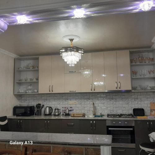 a kitchen with white cabinets and a chandelier at Nugzar House Chakvi - 2 Bedrooms in Chakvi