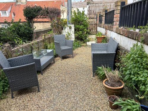 a group of chairs and a table in a garden at Saltwick Cottage in Whitby