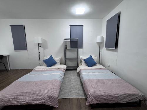 two beds in a room with blue pillows at Cozy Rustic Corner House Subic in Subic