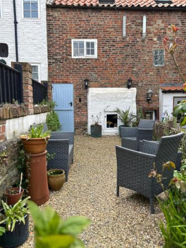 a courtyard with chairs and a fireplace in a brick building at Saltwick Cottage in Whitby