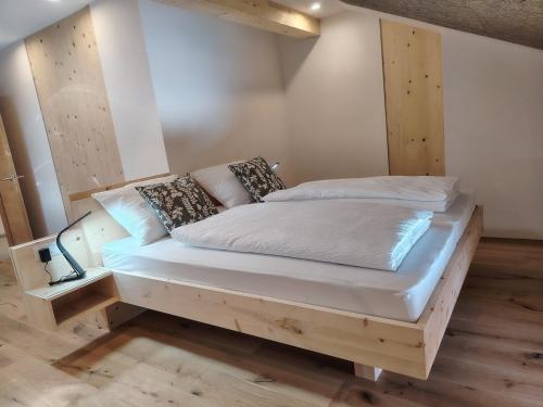 a bedroom with a wooden bed with white sheets and pillows at Laimbruchhof Apartments Urlaub auf dem Bauernhof in Val di Vizze