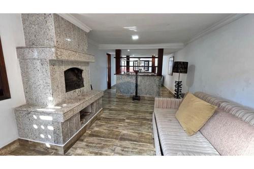 a living room with a stone fireplace and a couch at Casa Indaiá in Petrópolis