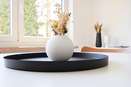 a white vase sitting on a table with a plate at stycoz - Modern studio - Close to the lake in Starnberg