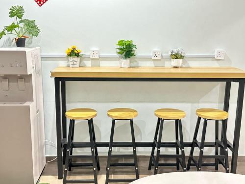 a bar with four stools under a counter with plants at Hotel O Kledang Menglembu in Ipoh