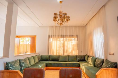 a living room with a green couch and a chandelier at Villa Park Marrakech in El Aggada