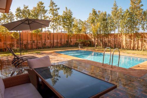 a swimming pool with a chair and an umbrella at Villa Park Marrakech in El Aggada